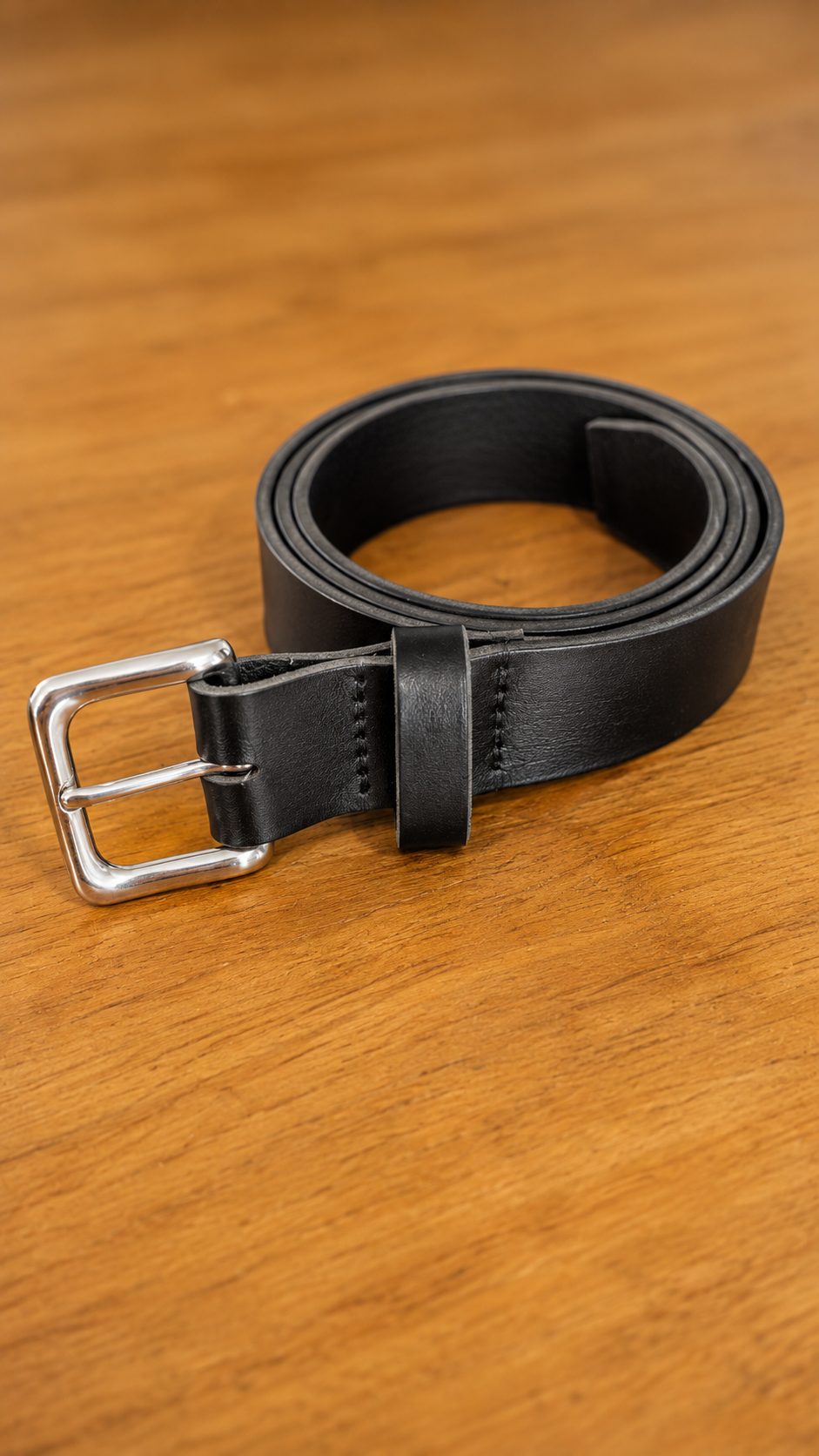 A black leather belt with a stainless roller buckle, restitched and re-holed