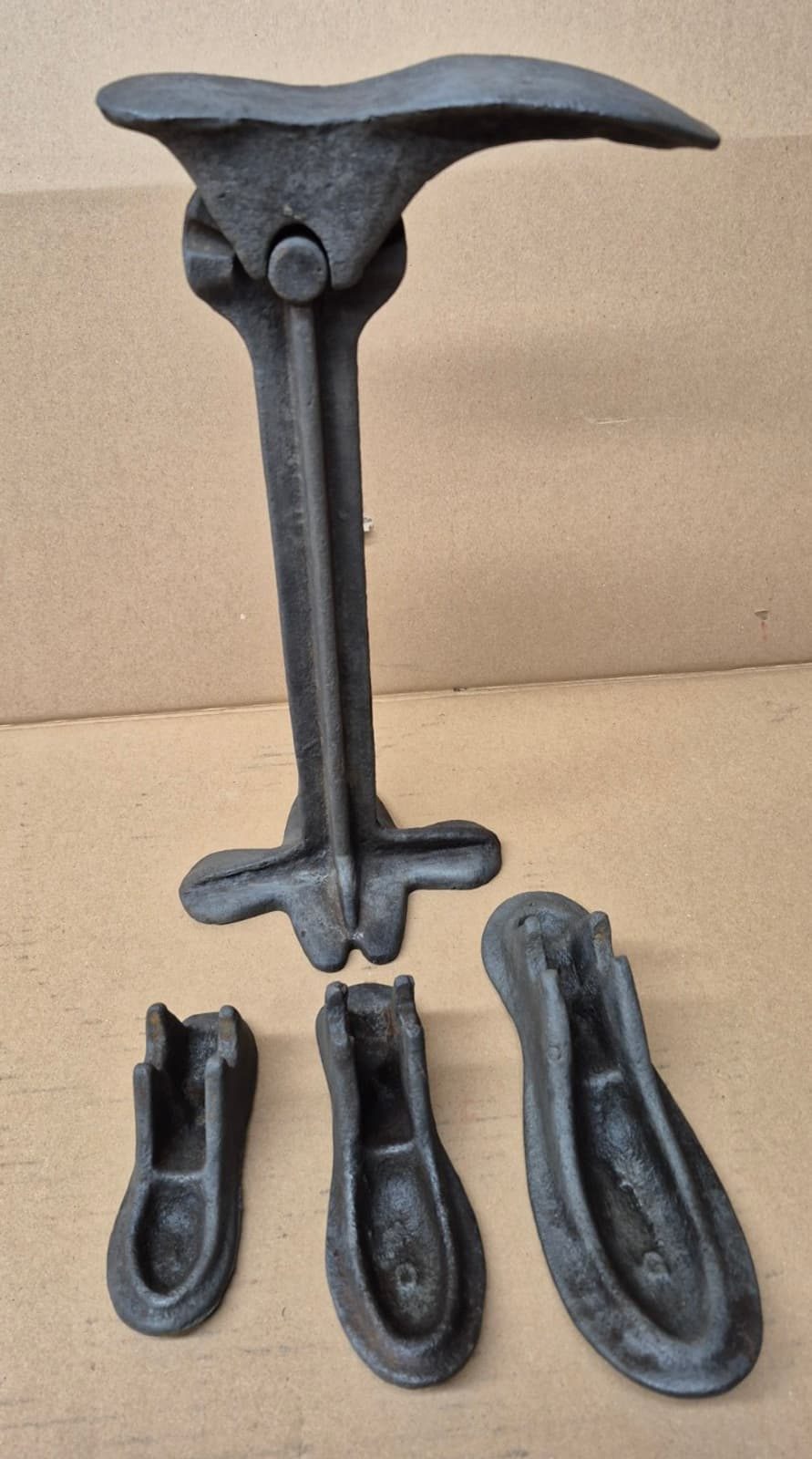 A cast-iron cobbler's last stand with three interchangeable foot plates in different sizes